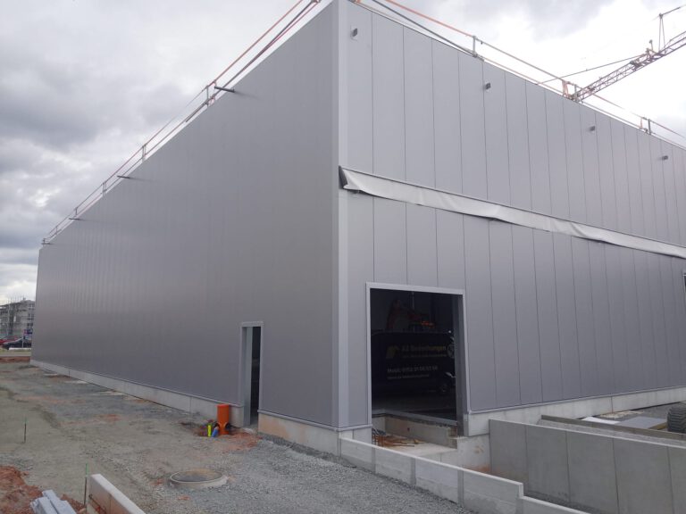 Bauvorhaben Stahlgruber Kaiserslautern: Moderne Fassade mit grauen Sandwichpaneelen und großem Toröffnung