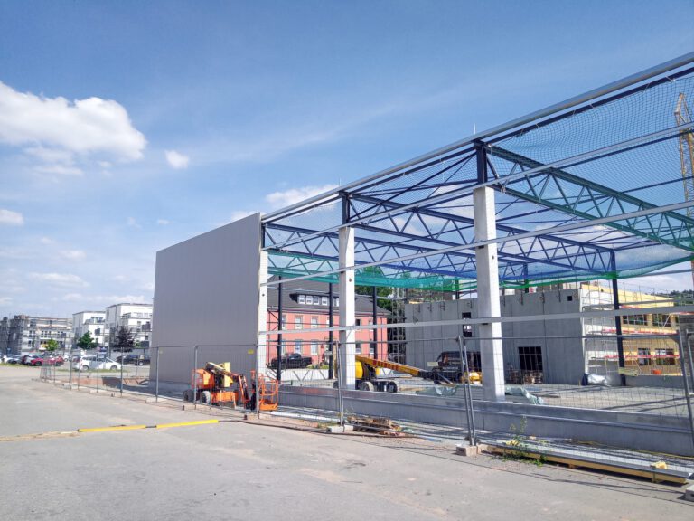 Bauvorhaben Stahlgruber Kaiserslautern: Fassadenverkleidung mit anthrazit Sandwichpaneelen und Sicherheitsnetz