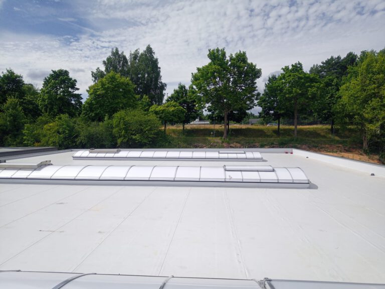 Flachdachsanierung in Neunkirchen: Fertige lichtgraue Folienabdichtung mit mehreren Lichtkuppeln und Oberlichtern im Saarland