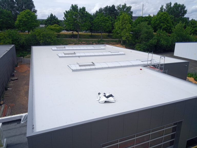 Flachdachsanierung in Neunkirchen: Frisch verlegte lichtgraue Folienabdichtung mit langen Lichtbändern im Saarland