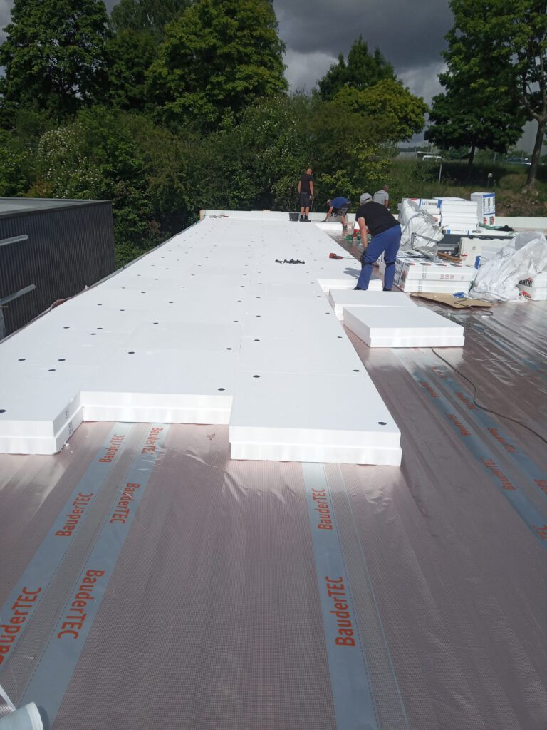 Bauvorhaben Profile Neunkirchen Flachdach: Montage von weißer PIR-Dämmung auf Flachdachabdichtung im Saarland