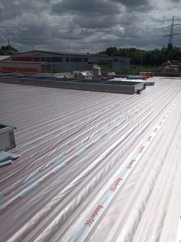 Flachdachsanierung bei Profile in Neunkirchen: Verlegung von BauderTEC Dampfsperrfolie auf großer Flachdachfläche im Saarland